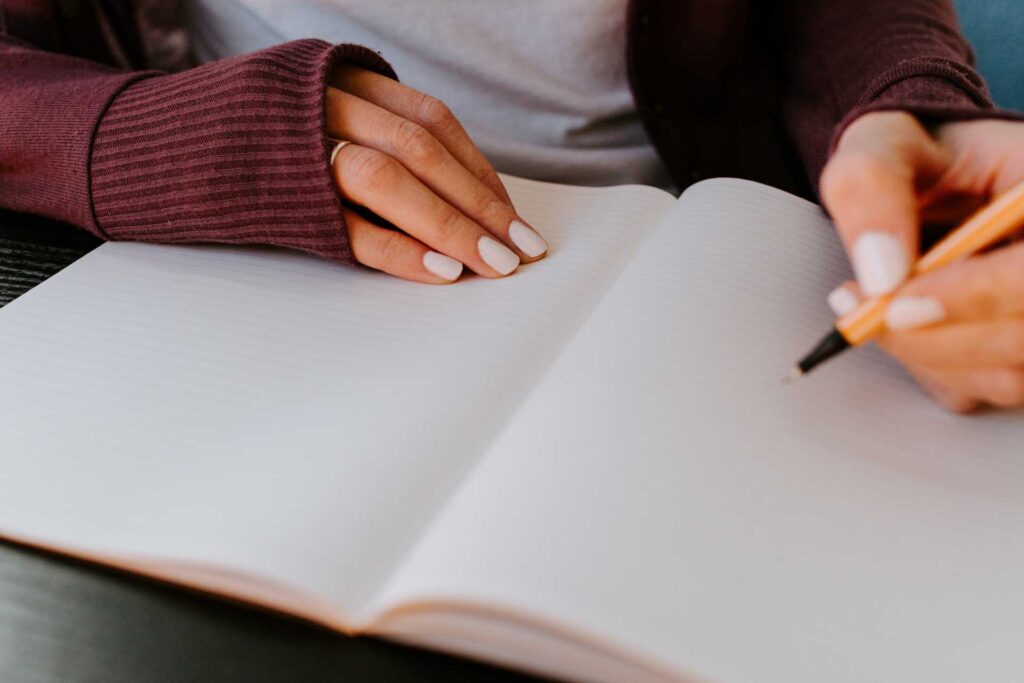 Woman writing self discipline affirmations in a blank page of a journal