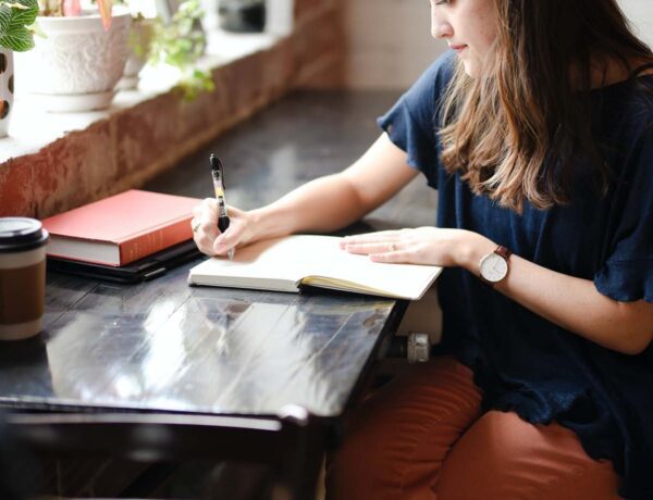 Woman writing in journal using positive journal prompts