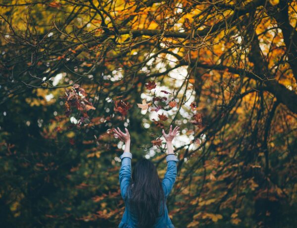 Woman throwing leaves in the air, one of my favorite Fall bucket list ideas
