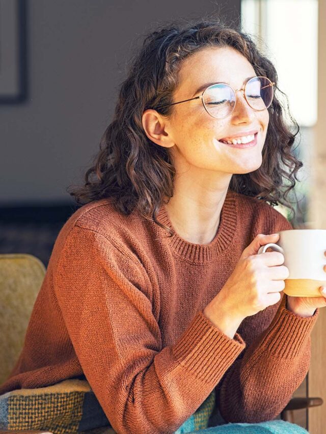 woman smiling while enjoying a cup of coffee